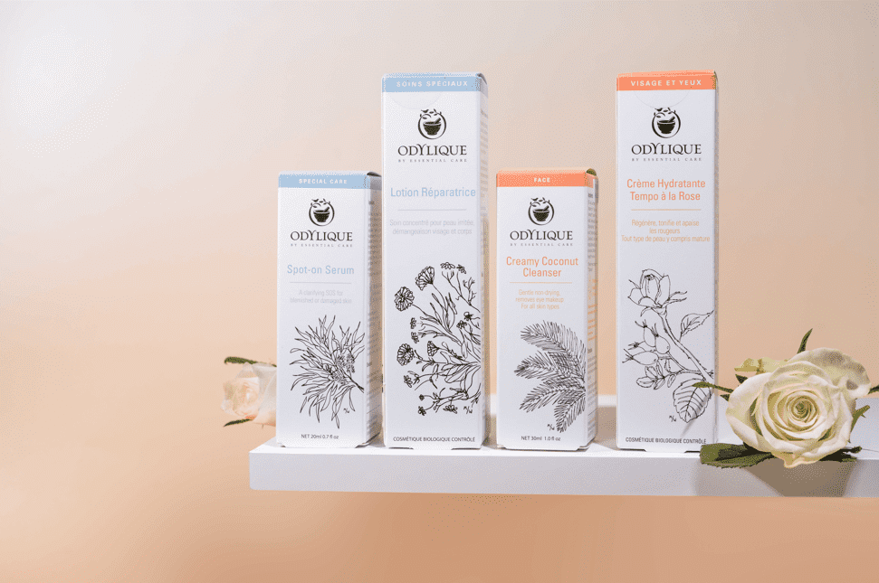 alt="Odylique organic skincare lineup on a white shelf with roses: Spot-on Serum, Repair Lotion, Creamy Coconut Cleanser, Rose Moisturiser."